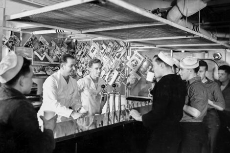 Sailors enjoy a break at the soda fountain aboard the USS Brooklyn on Jan. 18, 1938. Hanging from the wall are a variety of pulps from early 1938, including Sport Story Magazine, Thrilling Mystery, Clues Detective Stories, Thrilling Detective, Breezy Stories, Doc Savage, The Phantom Detective, Weird Tales, and Romantic Range.