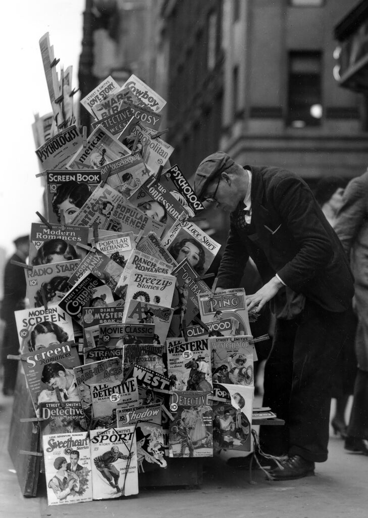 Pulps and a few “slicks” are clipped to the side of this magazine rack in New York City in November 1932.