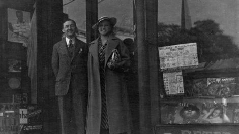 A man and woman pose in front of a store, where displayed in the right window are copies of "Dare-Devil Aces" (June 1938), "Lone Eagle" (June 1938) and "Knockout Magazine" (June-July 1938).