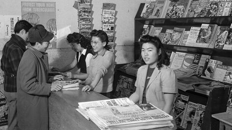 Pulps — including "Thrilling Wonder Stories," "Thrilling Adventures," "Jungle Stories," "Weird Tales," "North West Romances," and more — hang on the wall and on the shelves behind the counter of the magazine stand in the Granada War Relocation Center, a Japanese American internment camp in southeast Colorado, during December 1942.