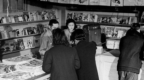 Interned Japanese-Americans shop at the magazine stand in the Tule Lake War Relocation Center in California in March 1944. Several sports pulps from around that time are displayed on a shelf in the background.