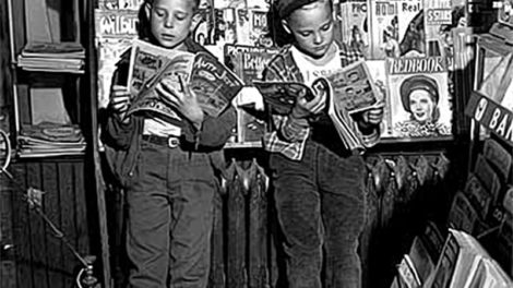 Two boys read comic books at a newsstand in September 1946. Pulp are stacked on the shelves along the left-side of the photo.