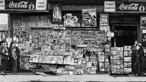 Publications are almost falling off this overly loaded newsstand at East 32nd Street and Third Avenue, New York City (date unknown).